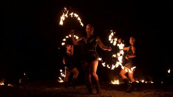 慢动作:专业的火焰表演三个女人拿着火把一个男人拿着火焰喷射器
