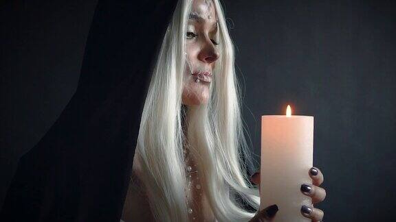金发女人骷髅头黑色斗篷手里拿着燃烧的蜡烛