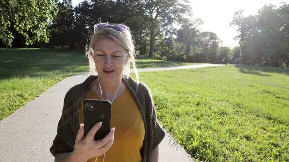 老妇人在春日户外公园用手机进行视频通话慢动作视频