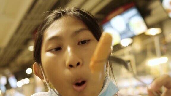 亚洲女学生穿着制服和她哥哥在美食广场吃香肠生活理念