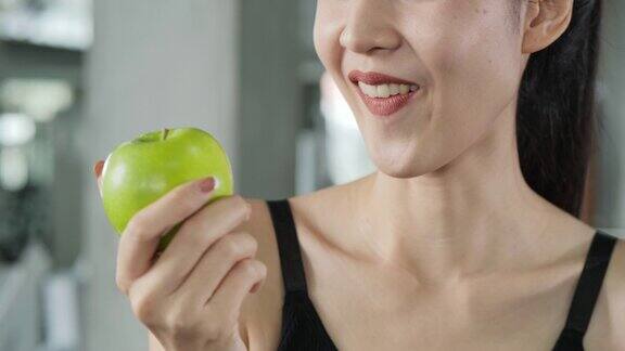 特写亚洲美丽的女人在健身房咬青苹果