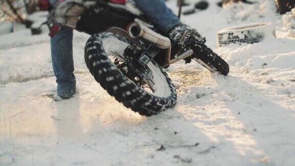 摩托车手在雪地上轮胎烧坏慢镜头夕阳西下专业的摩托车手在雪地上滑行和转弯骑摩托车的人在摩托车上表演特技
