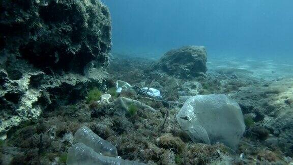 塑料污染了海底热带鱼游过海底覆盖着大量塑料垃圾地中海海床上的瓶子、袋子和其他塑料碎片