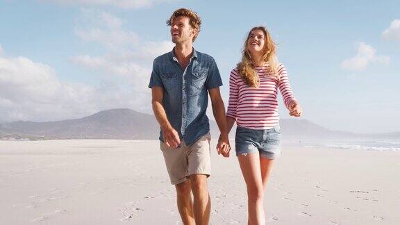 一对情侣在暑假一起沿着海滩散步