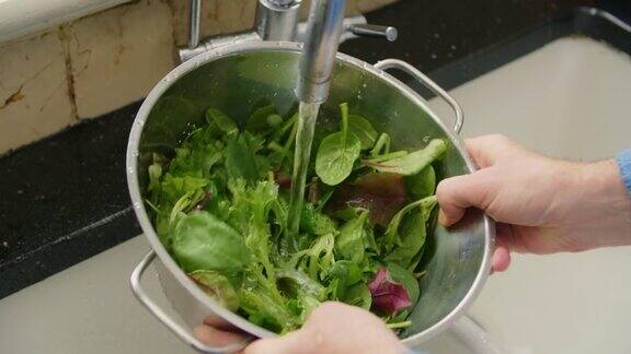 在滤锅里洗绿叶蔬菜时男人在发抖
