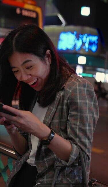 垂直视图:年轻的亚洲妇女在城市发短信手机