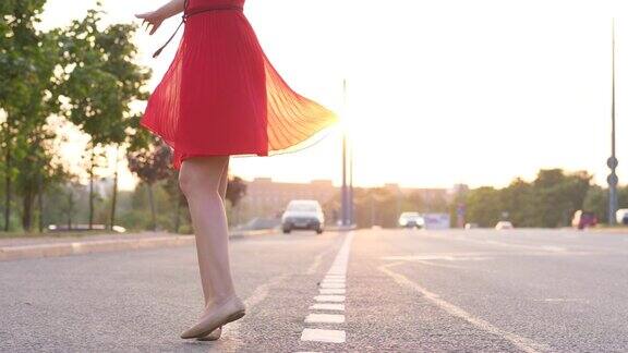 快乐的女人穿着红裙子跳舞在路上转身