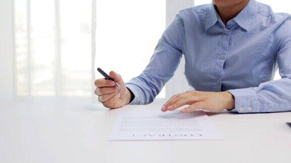 女商人带着房子模型和钢笔在办公室签署合同文件