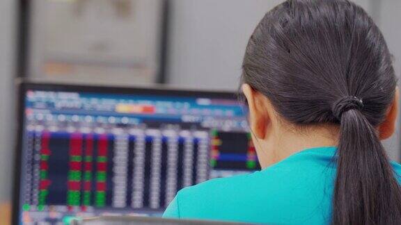 女商人坐在笔记本电脑前屏幕上是证券交易所