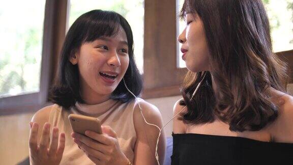 两个亚洲女性朋友用手机一起笑