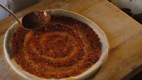 意大利菜在烤箱里烤披萨厨师把番茄酱涂在披萨面团上