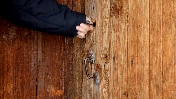 一名白人男子关上旧木门并锁上
