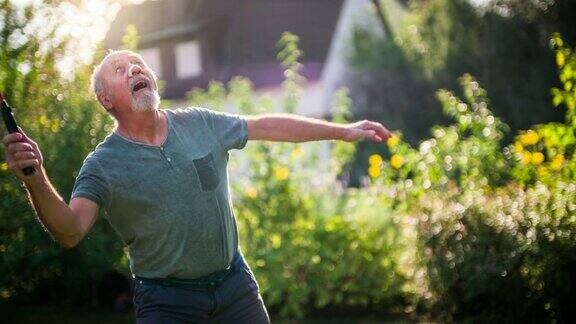 活跃的老年人在阳光灿烂的花园打羽毛球