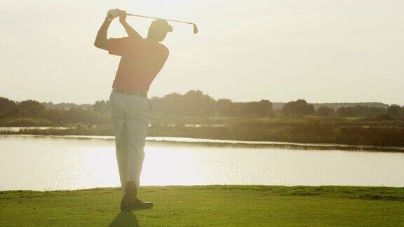 白种男性高尔夫球手在日落时击球