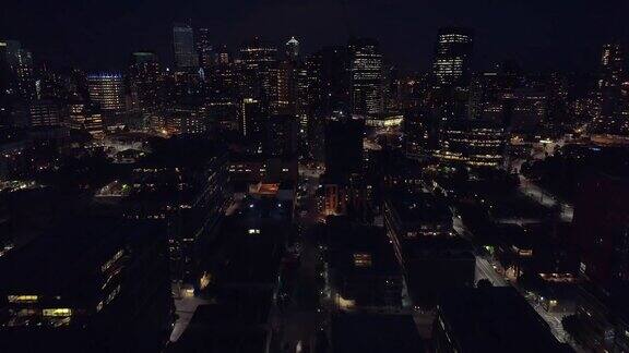 直升机在夜间展示城市的摩天大楼