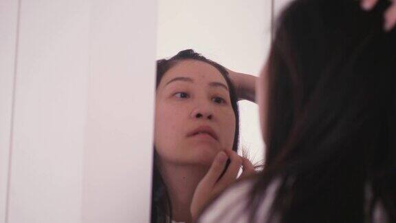 近距离的女人与痘痘在她的脸上概念而触摸她的痘痘在镜子