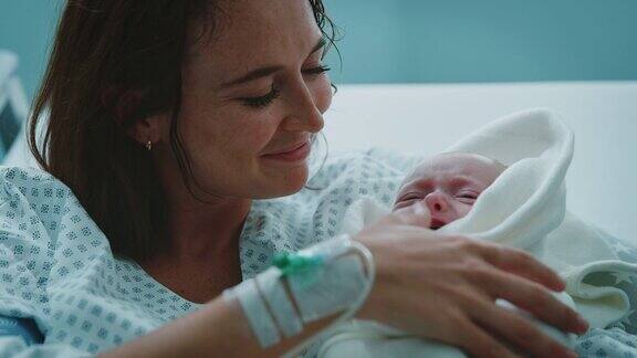 母亲看着婴儿在医院的床上哭泣