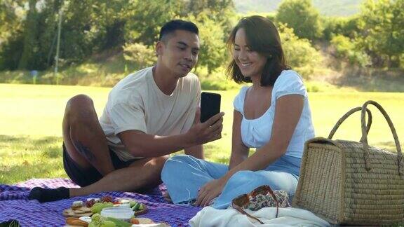 4k视频记录了一对年轻夫妇在外面的公园里约会用手机的画面