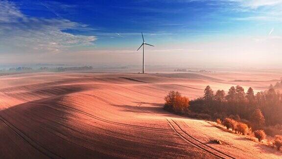 奇妙的雾风力涡轮机在棕色的田野在日出