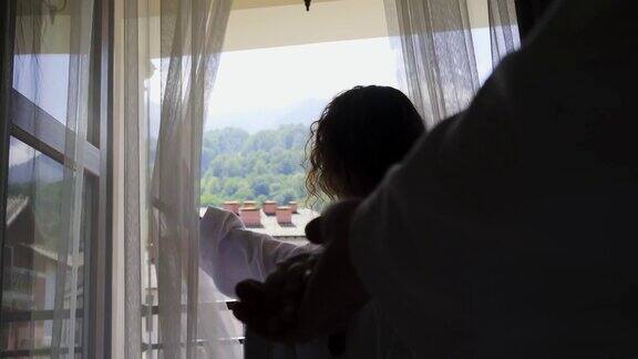 女人牵着丈夫的手走向窗前展示风景