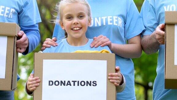 一队成人志愿者和孩子们拿着捐款箱微笑着慈善