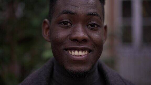 非洲黑人青年站在外面对着相机微笑肖像脸