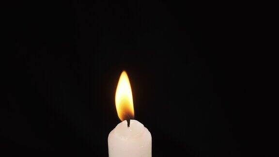 在黑色背景上点燃一支蜡烛照明蜡烛的火焰