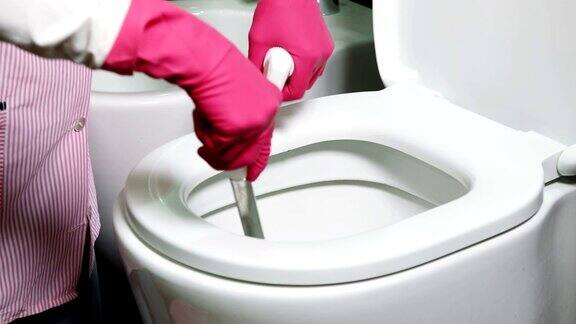 戴着粉色手套的女人在洗抽水马桶