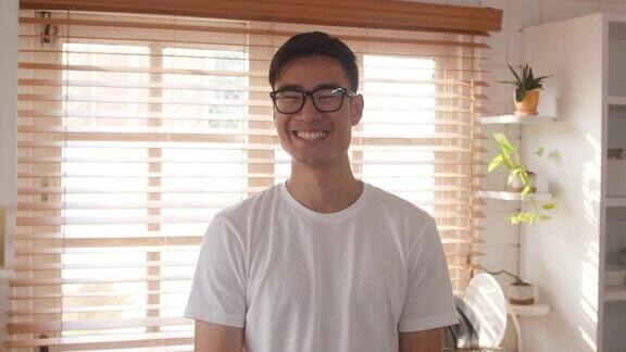 快乐的年轻亚洲男性感到幸福的微笑双臂交叉看着镜头而放松在厨房在家里