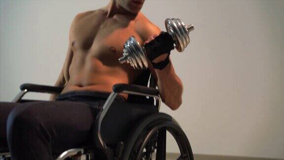 那个坐在轮椅上的残疾运动员正在用哑铃训练慢动作