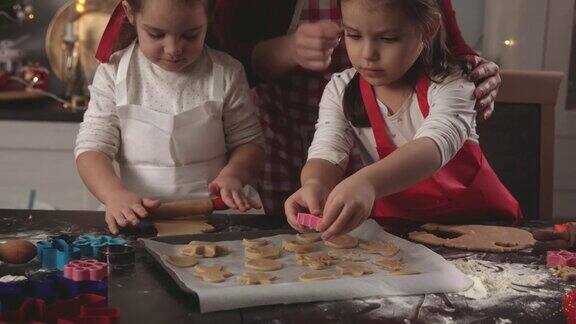 妈妈在帮她的两个小女儿做姜饼