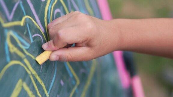小男孩用彩色粉笔在黑板上潦草地画着
