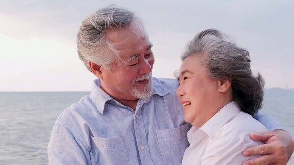 年长的亚洲夫妇站在海滩上心情愉快有生活方式、情感和退休观念的人