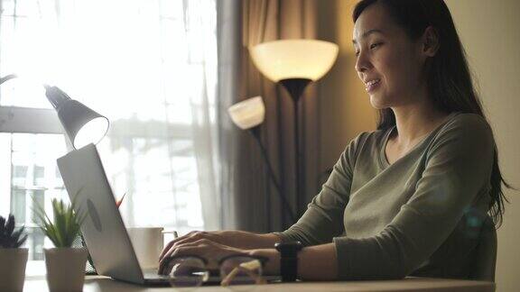 亚洲妇女在家里用笔记本电脑工作