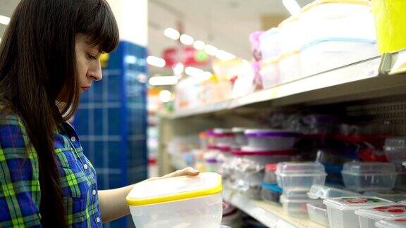 一位年轻的妇女在超市挑选并购买了一个装食物的塑料容器