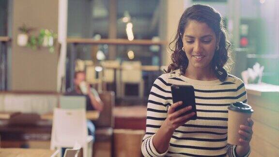 一名年轻女子用智能手机在咖啡馆喝咖啡的4k视频
