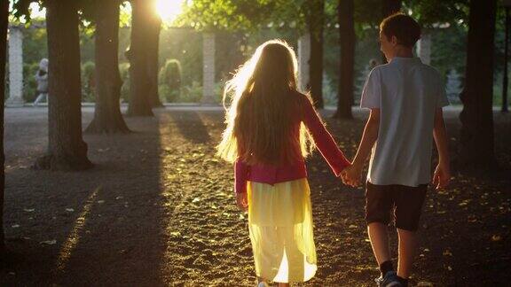 男孩和女孩手牵着手在公园里散步