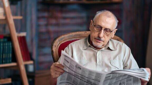 白发苍苍的老成男子戴着眼镜阅读日报印刷报纸的复古扶手椅
