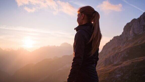 一个女人站在山顶欣赏日落的美景