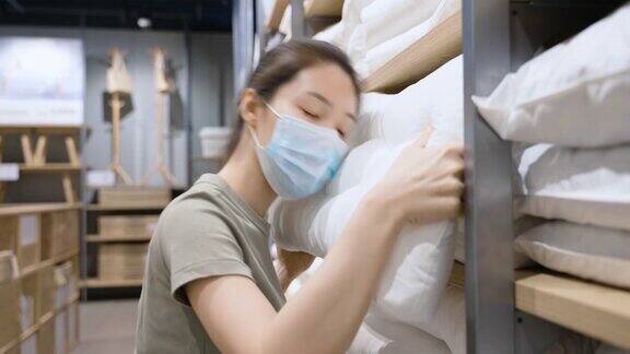 亚洲女性戴着防护口罩在零售店挑选枕头测试