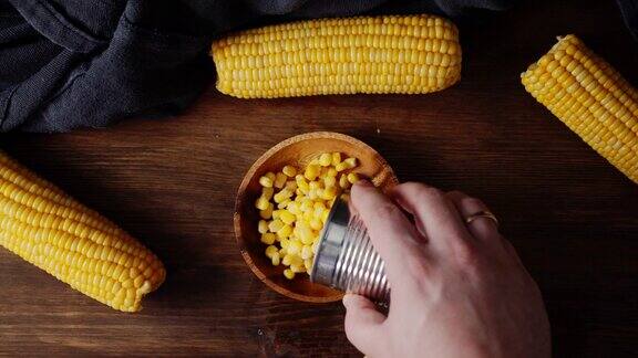 男性用手将罐装玉米倒在盘子里