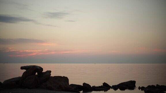 美丽的粉红色日落(日出)上的海面完全平静有海鸥在飞翔