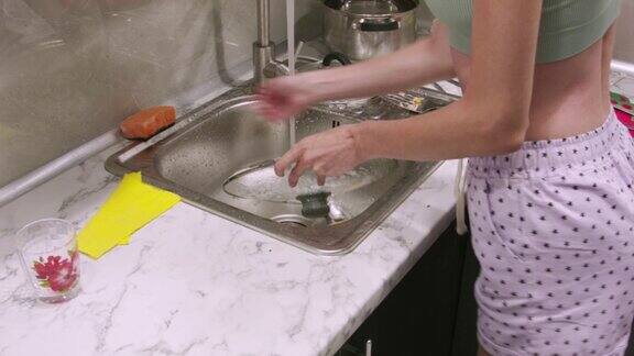 一个年轻女人在厨房水槽里洗煎锅盖的特写