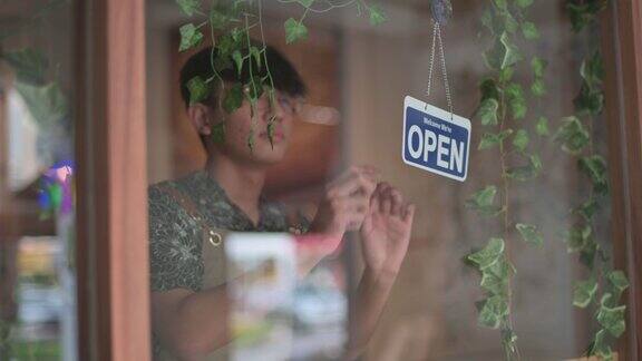 亚洲华人年轻的咖啡馆咖啡师服务员自助餐厅的工人把招牌从关闭到开放外的咖啡馆餐厅准备上午营业