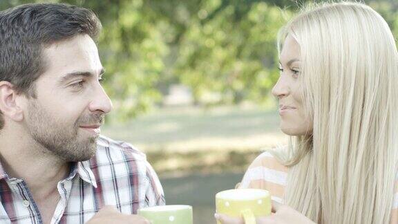 年轻夫妇坐在公园里喝咖啡