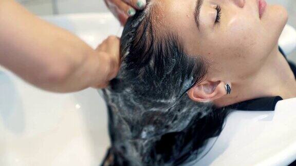 美发师在美容院给女人用洗发水洗头慢动作
