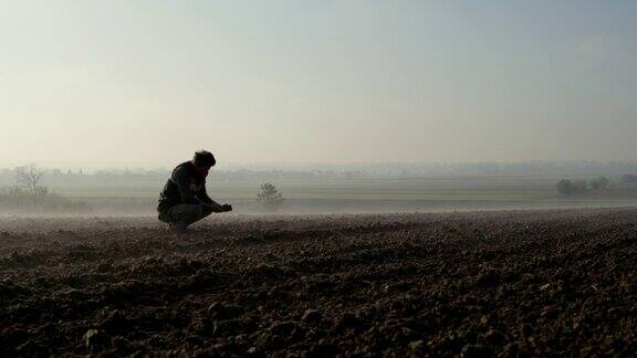 农民在被雾覆盖的土地上检查土壤