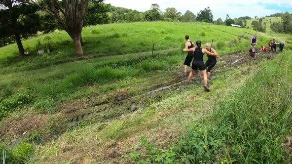 一群中年妇女在一个泥泞的泥潭中跑在越野障碍赛跑