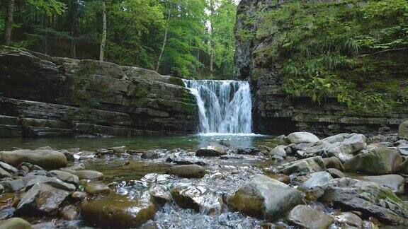 在夏季的森林里山河上的瀑布白色的泡沫水从岩石中落下