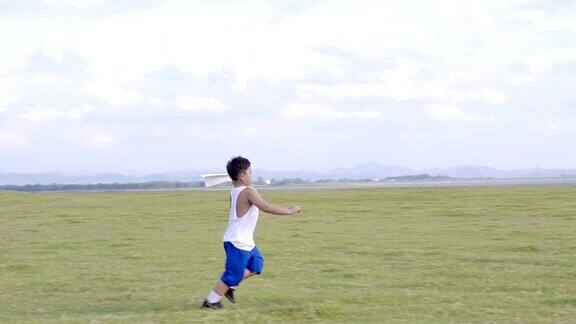 小男孩7岁快乐的在大自然的夏天在草地上奔跑和扔纸飞机日落时分4K视频慢动作